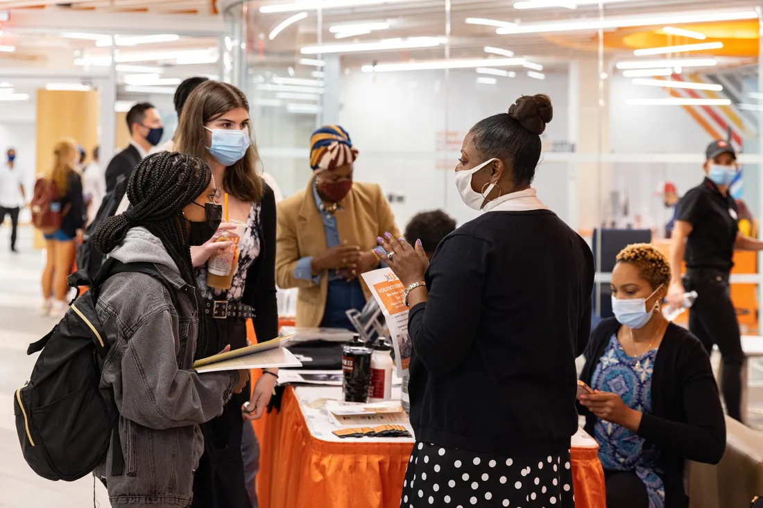 People stand around an information table in the Intercultural Collective