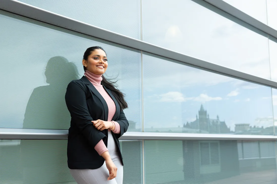 Portrait of Gharat leaning against a building and smiling.