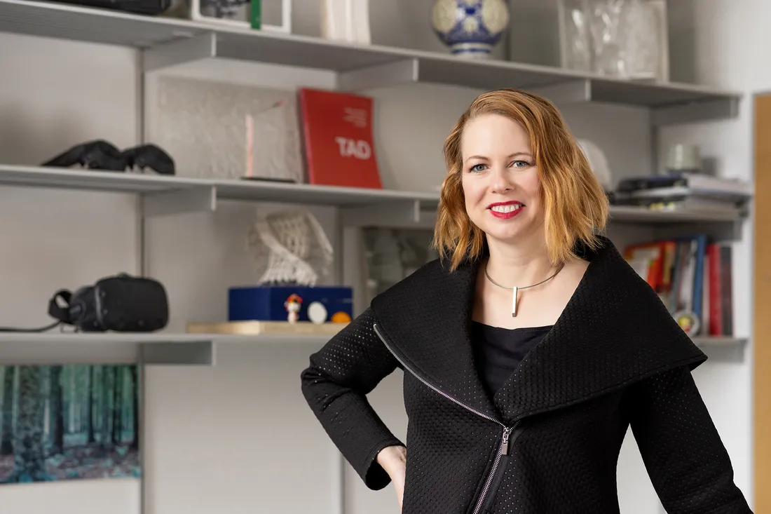 Portrait of Professor Amber Bartosh, smiling with one hand on her hip.