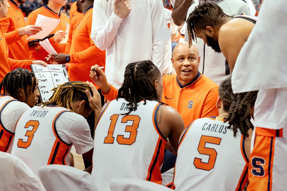 A Coach and team talking on the sidelines.