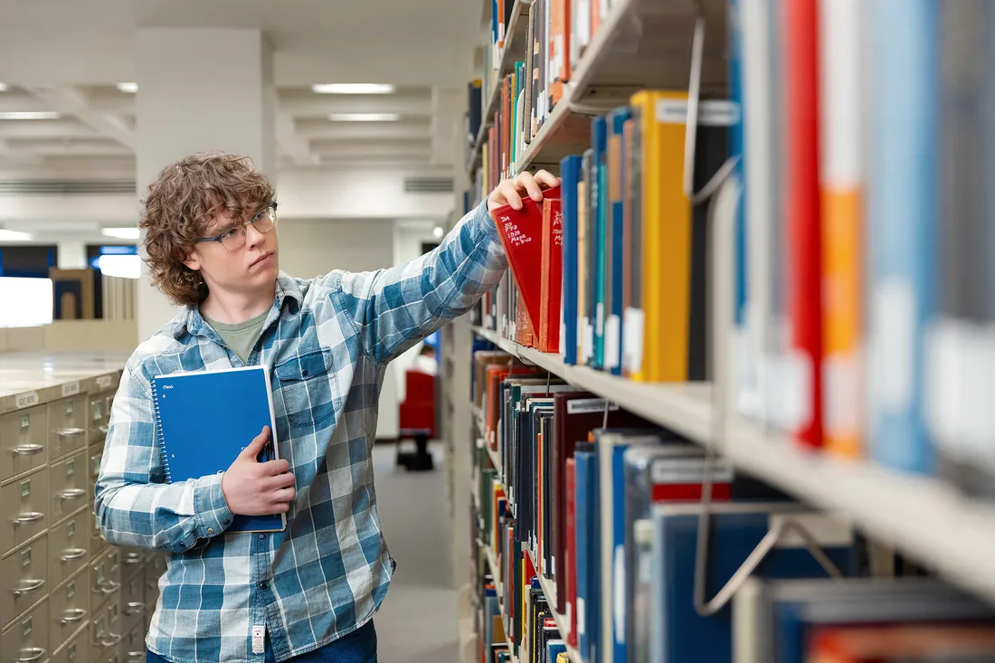 A student selecting books off of the shelf