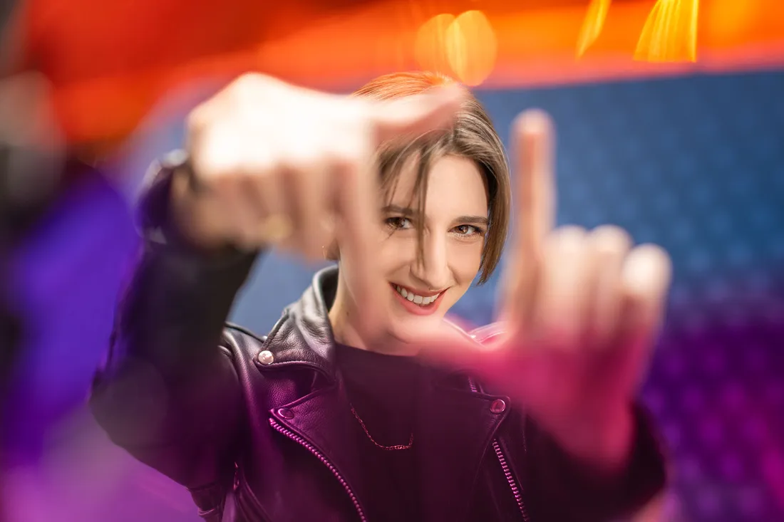 Warren making a square with her fingers in colorful light.