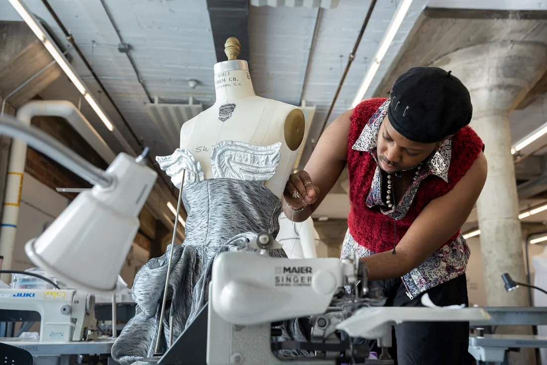 Photo of Williams using a needle and thread on a garment.