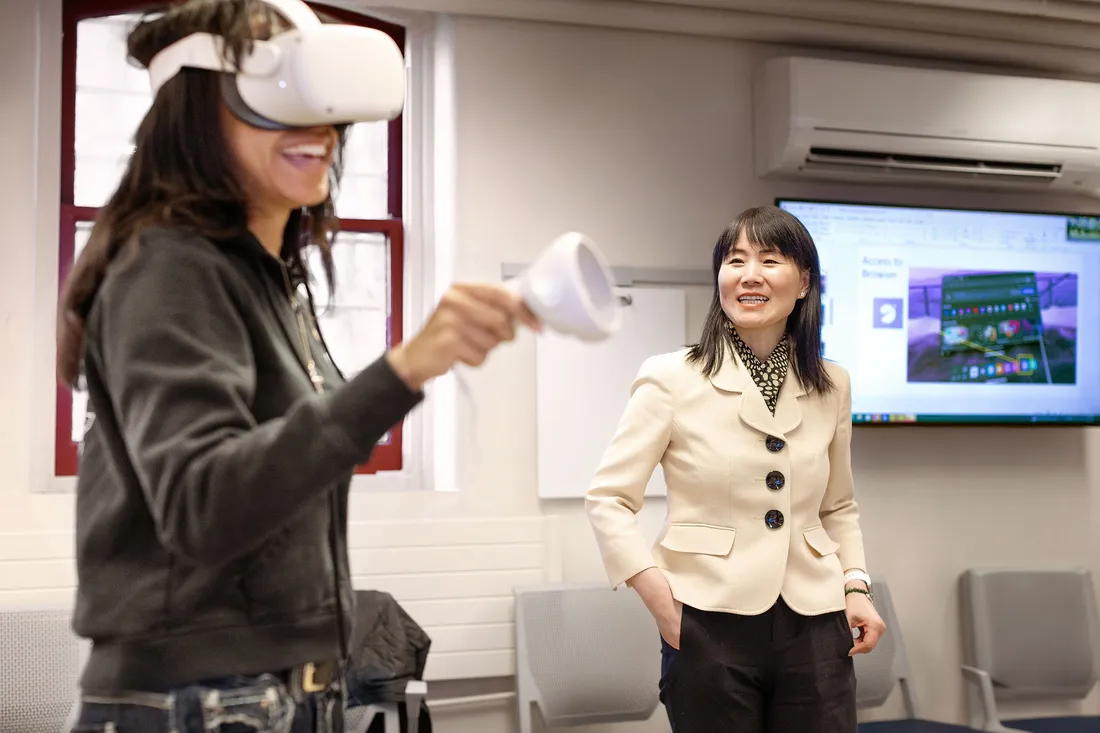 Teacher watching a students use a VR headset in the classroom.