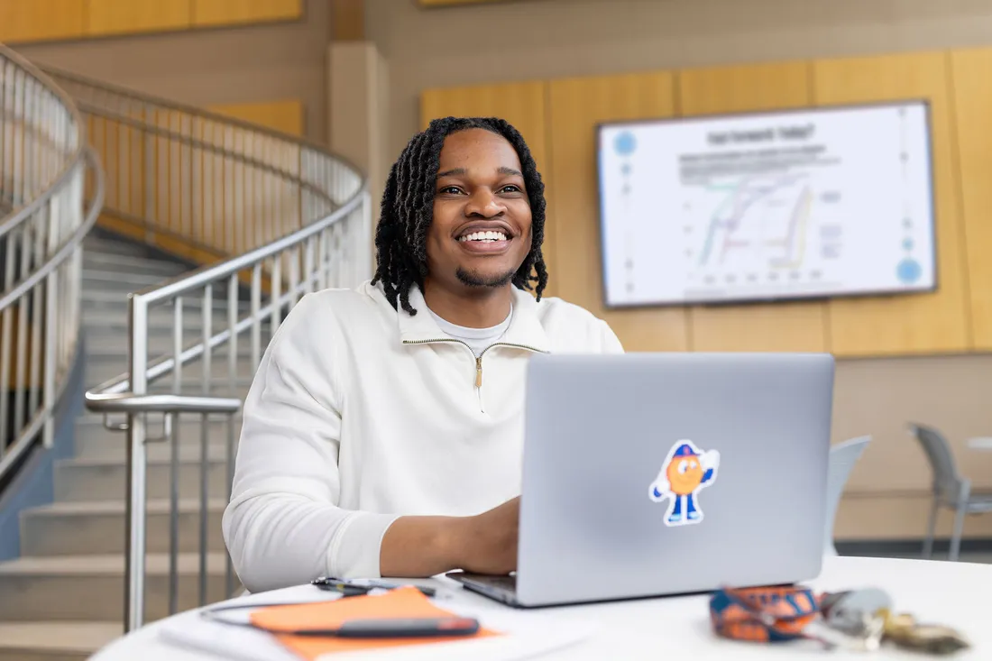 Student smiling while working on laptop.