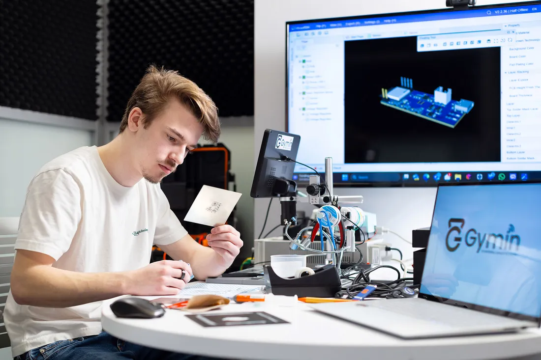 Student studying card in front of multiple monitors