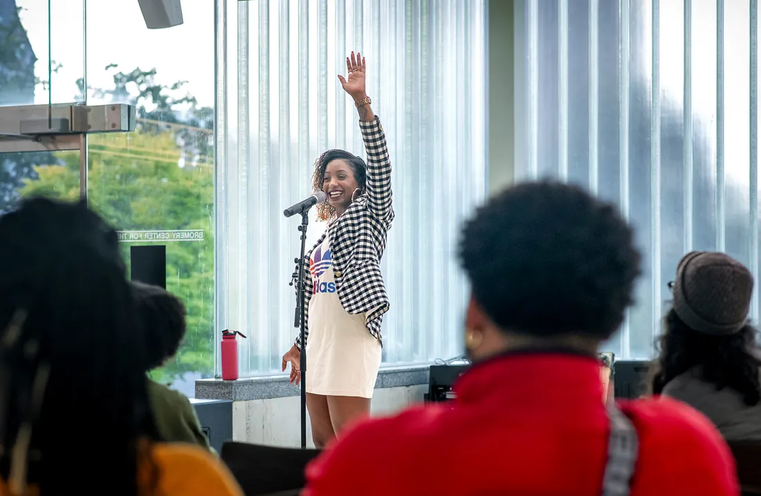 Imani Wallace speaking to a crowd and raising her hand.