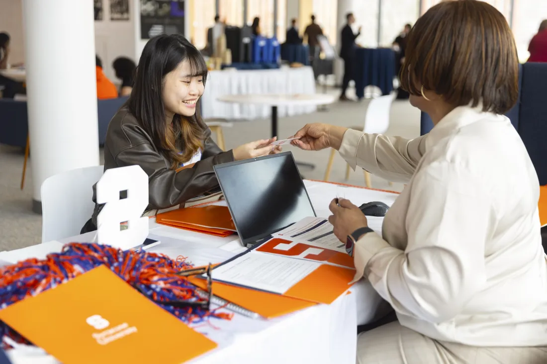 Student attending the Syracuse University Career Conference getting information from an industry professional.