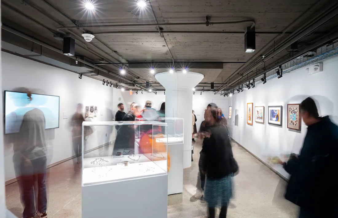 People walking around and looking at art at the Syracuse University Warehouse Gallery.