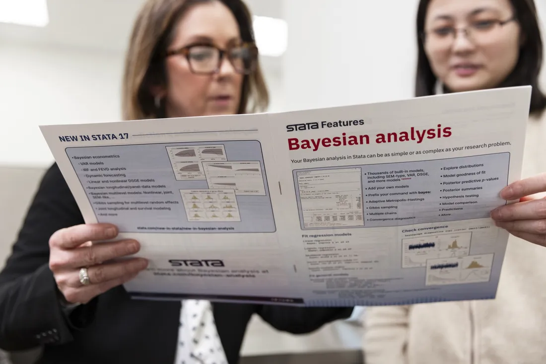 Two people holding a pamphlet about Bayesian analysis.