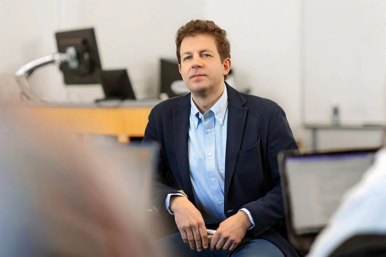 Professor sitting and smiling at camera.