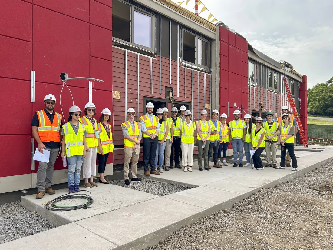 Partners of the Sustainable South Campus project wearing construction equipment lined up in front of the retrofitted apartments.