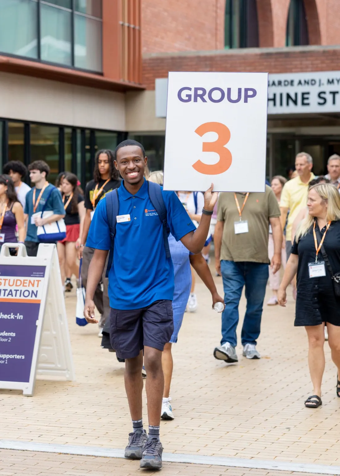 Orientation leaders at Syracuse University holding up a sign during a campus tour.