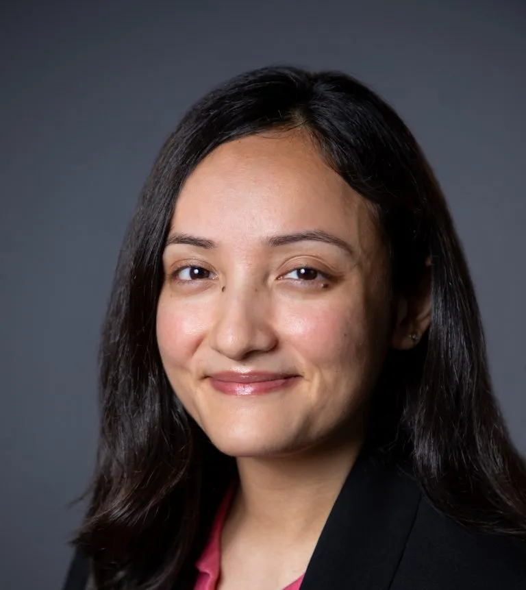Sharanya Kanwar smiling in a black blazer.