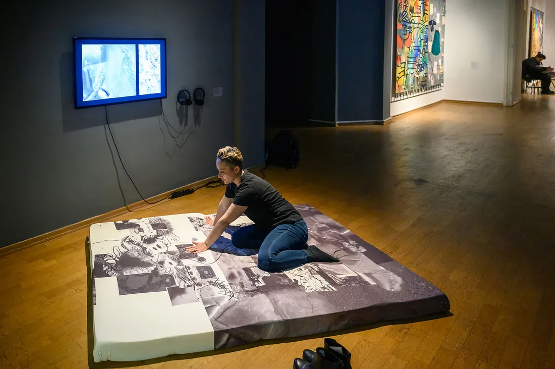 Artist sits on memory foam art piece.