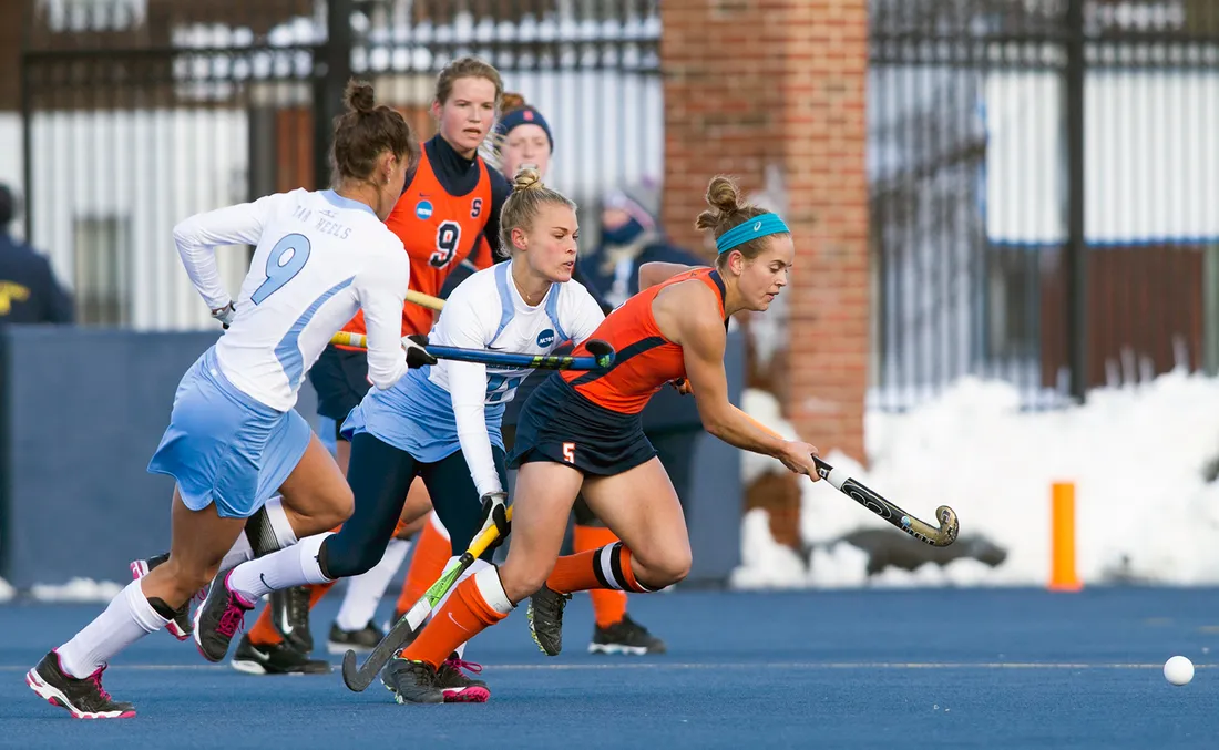 Women on field in middle of field hockey game.