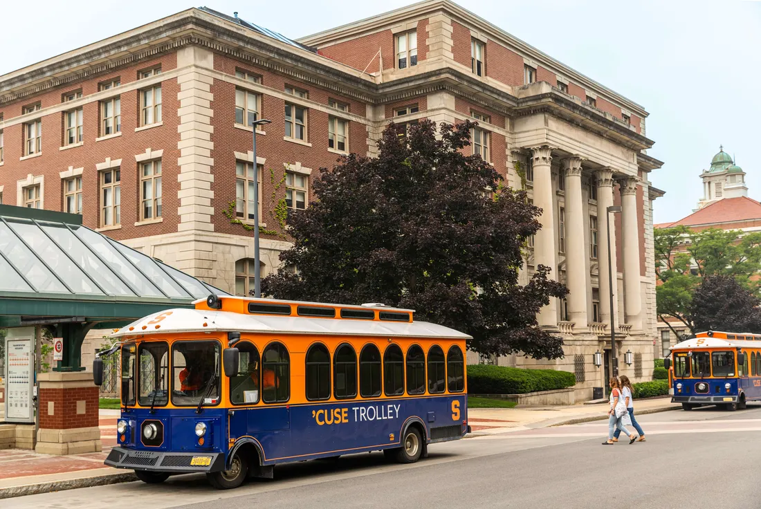 A Cuse trolley bus sitting outside a building on Syracuse University's campus.