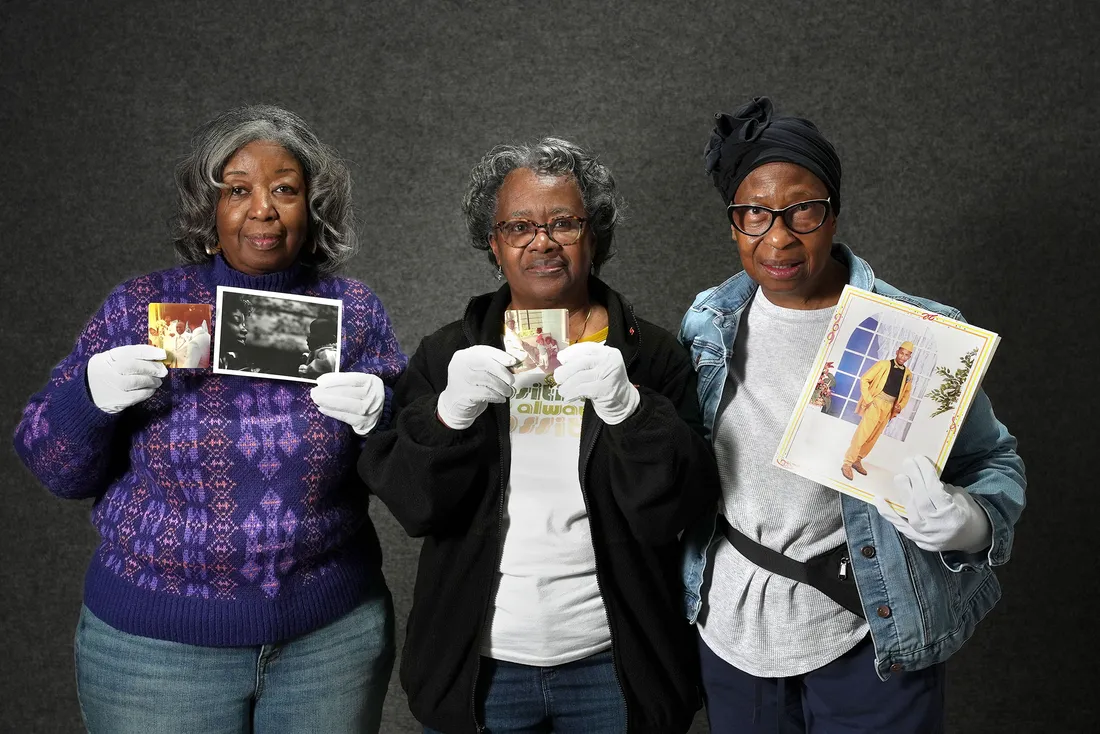 Three women standing and holding images.