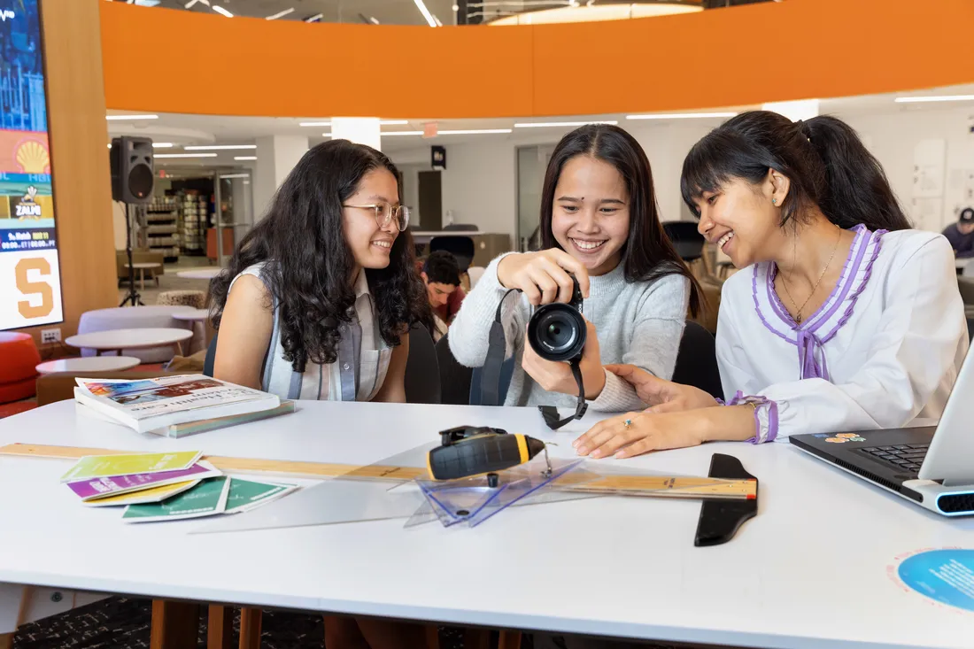 Three students look at camera together and smile.