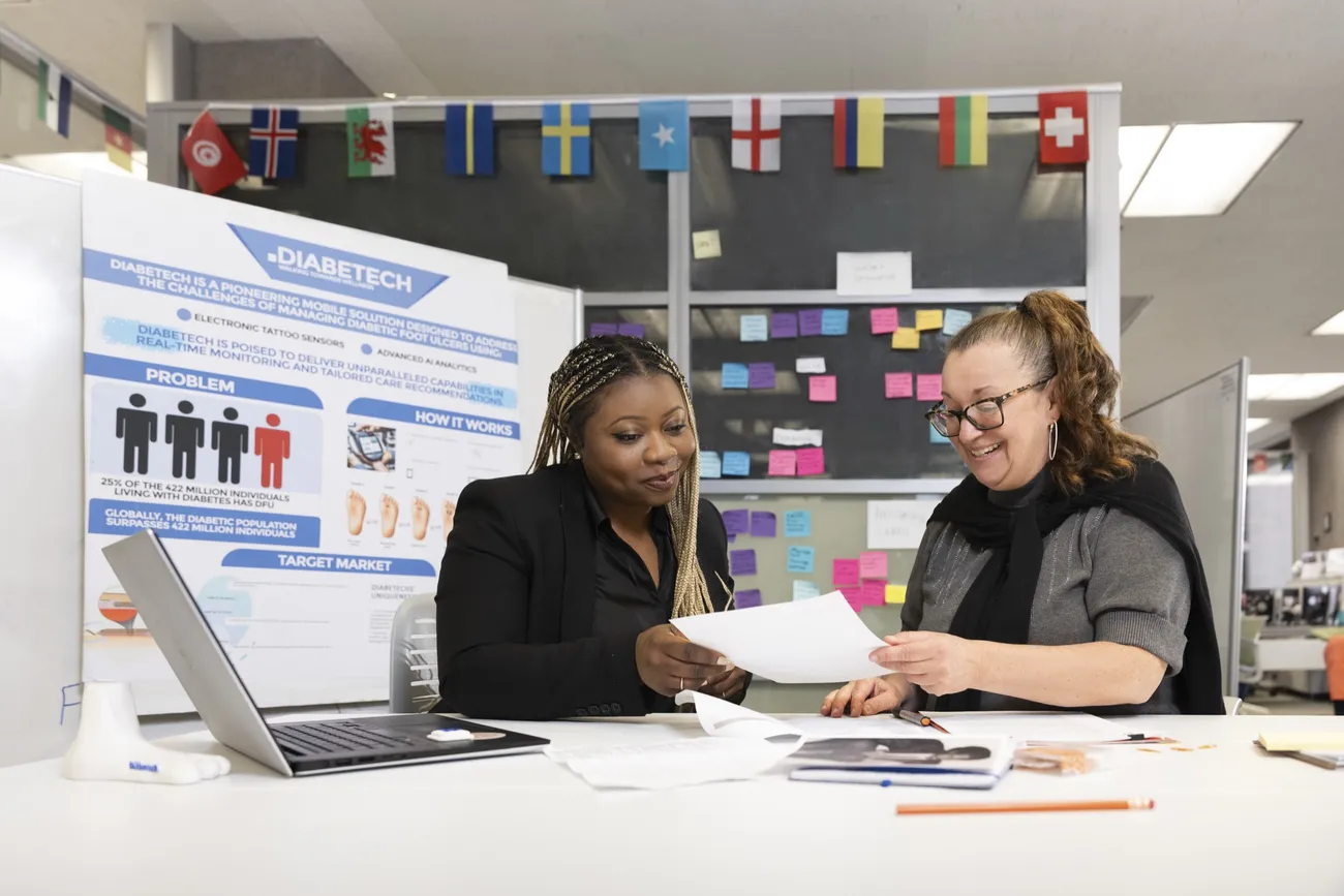 Tosin Alabi '25 working alongside a professor in Syracuse University's Bird Library.