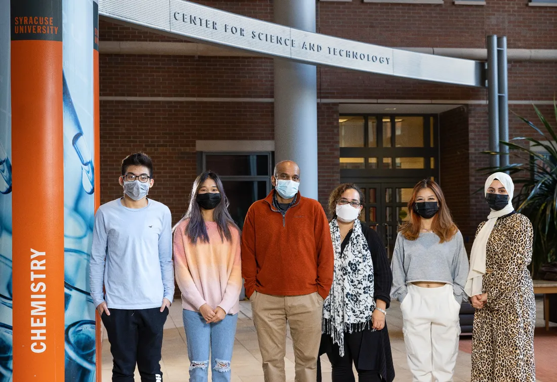 two faculty and four students standing in a spacious room