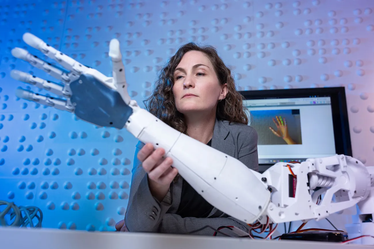 Professor Jaime Banks is working on a robotic arm.