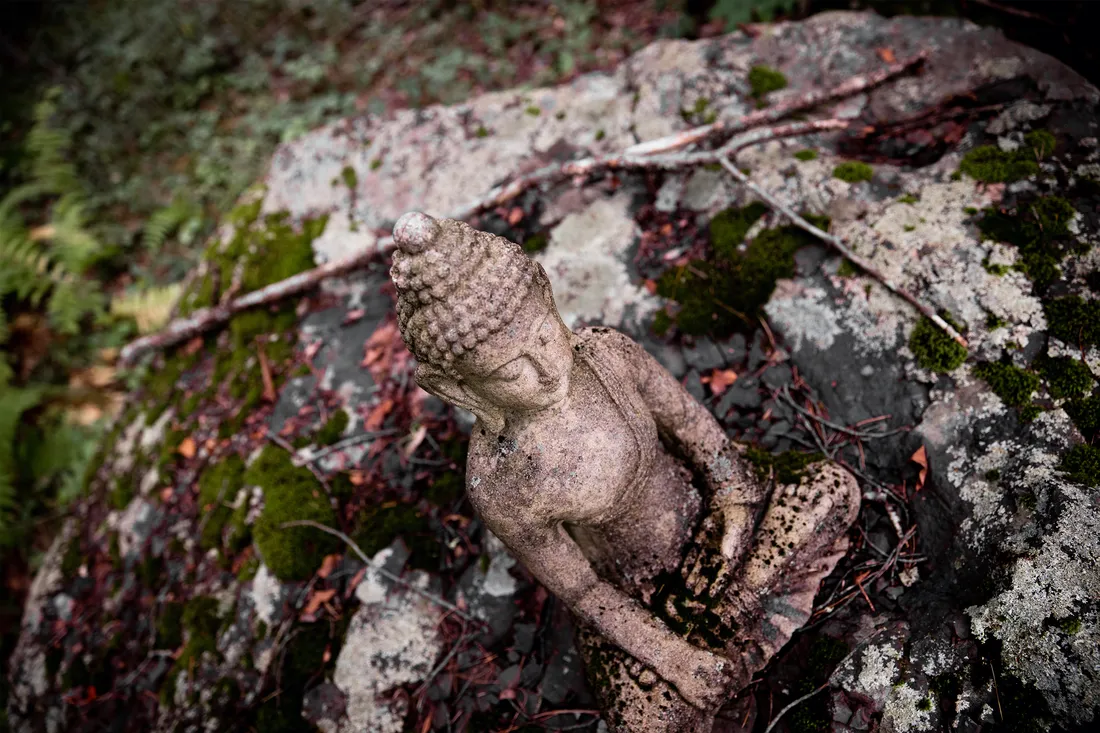 Close-up of a Tibetan statue on the ground outside.