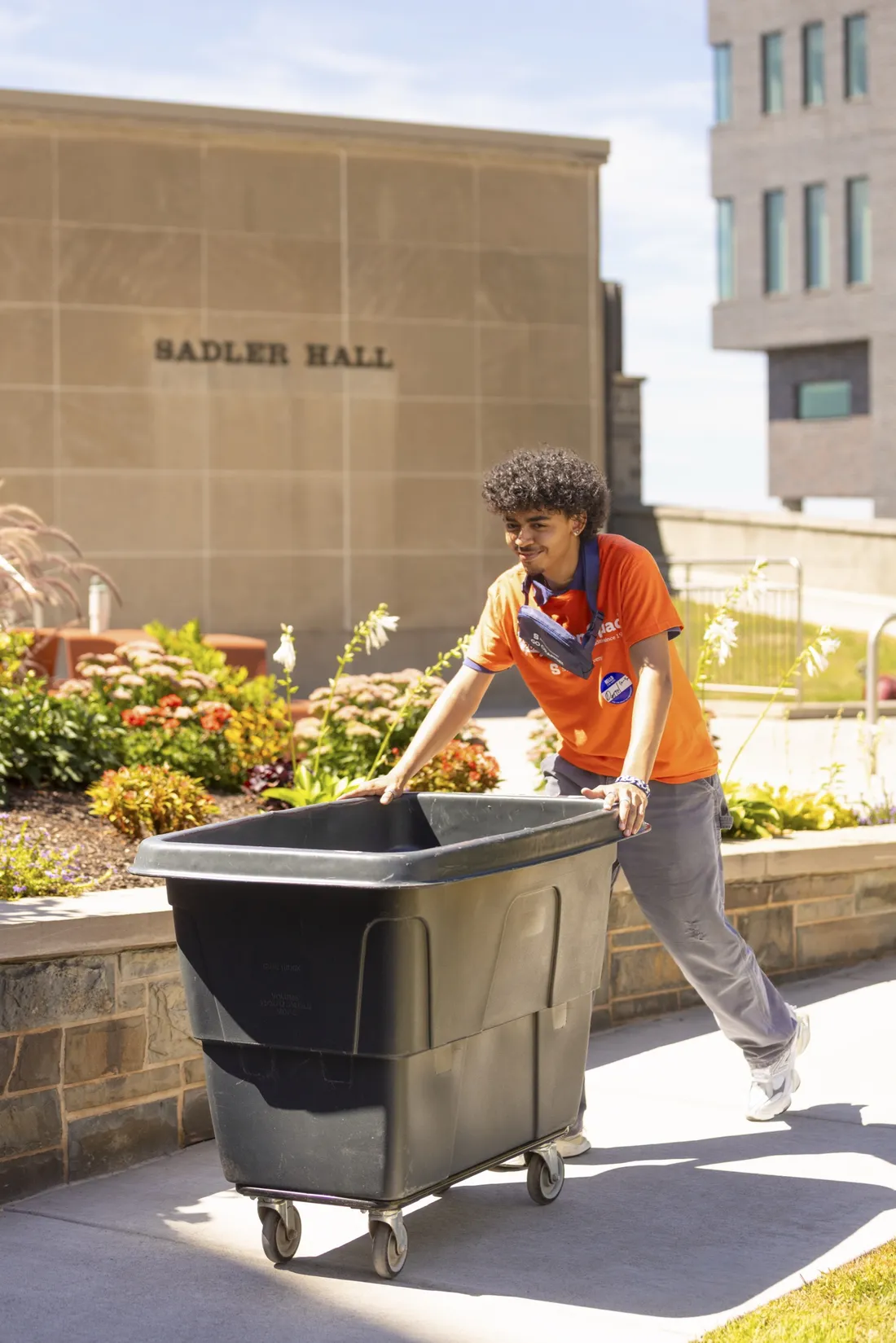 Student worker pushing a cart outside of Sadler Hall.