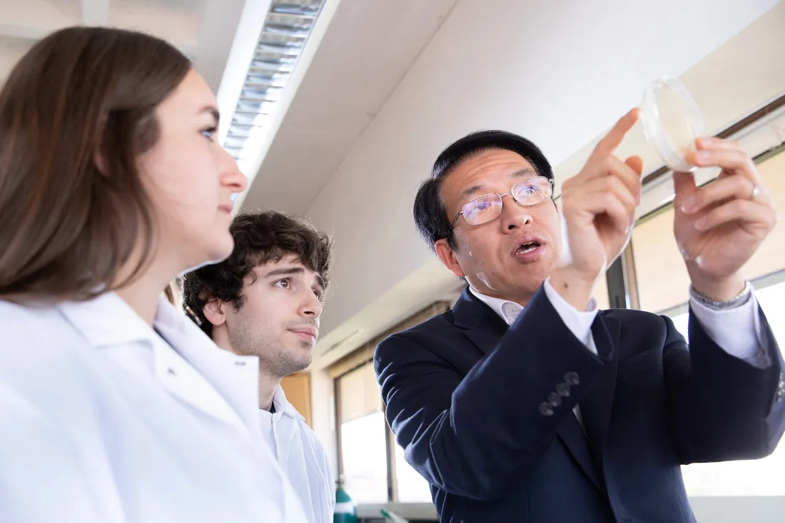 Three scientists interact in lab.