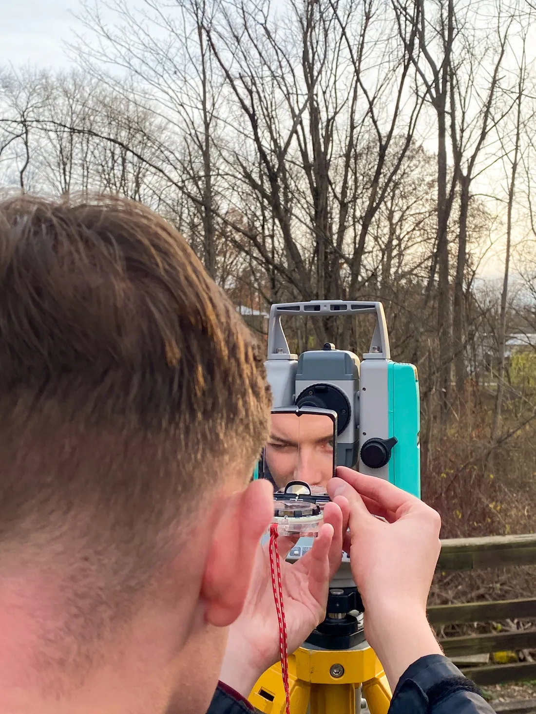 Person using survey equipment outside.