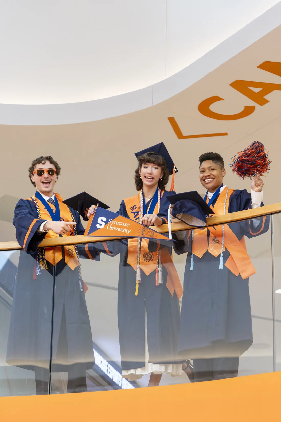 Thalia Lee '26 smiling in her graduation regalia, standing next to fellow Student Marshals Bobby Marie Battle and Steven Labovitch.