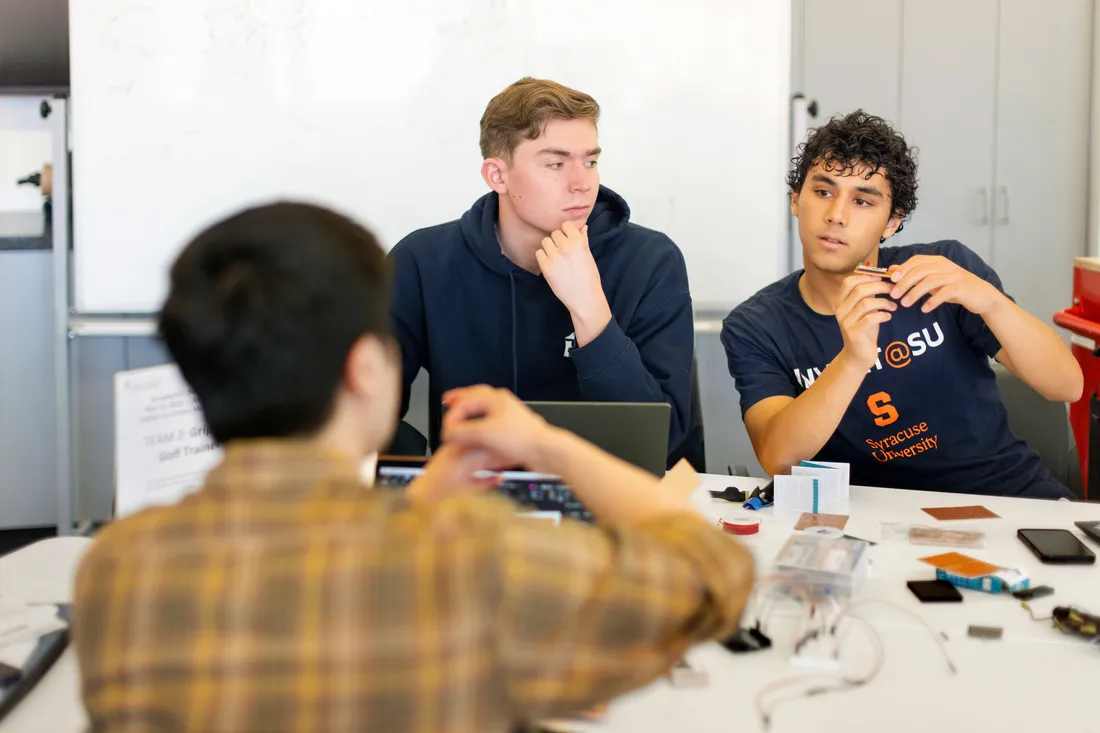 Three people sitting at table talking to each other.