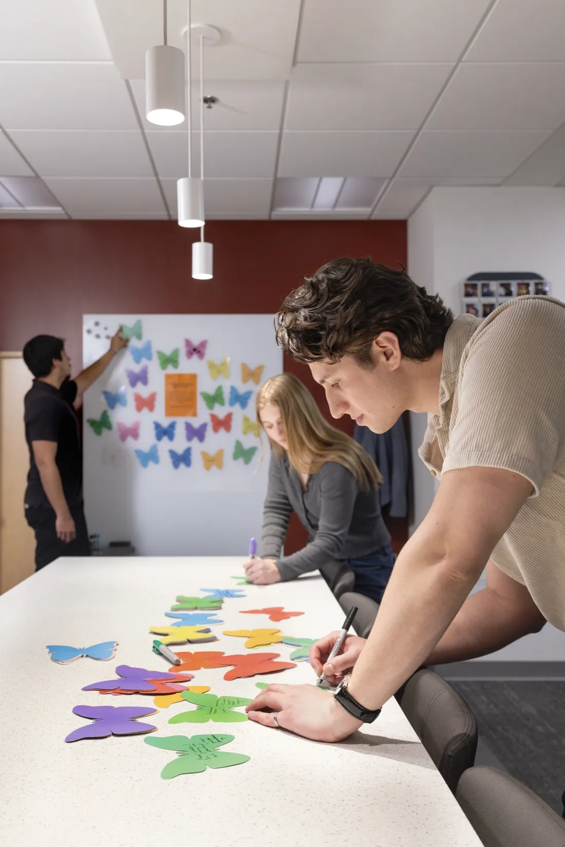 Christopher Prestia '26 writing positive notes on paper butterflies in the Campos Student Center.