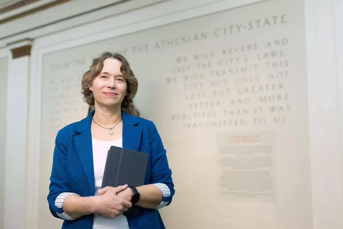A professor standing in front of a wall that has writing