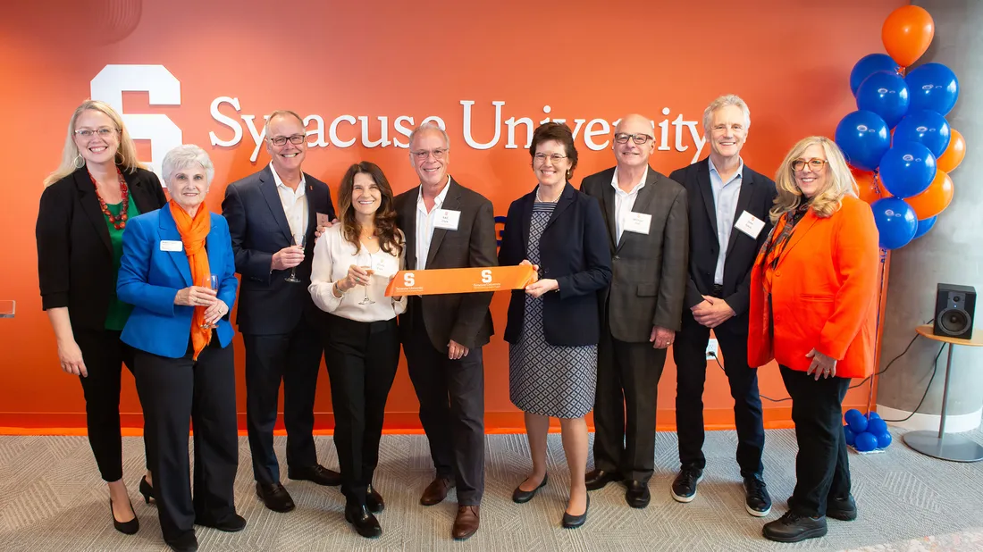 Group of people posing at ribbon cutting for new academic building.