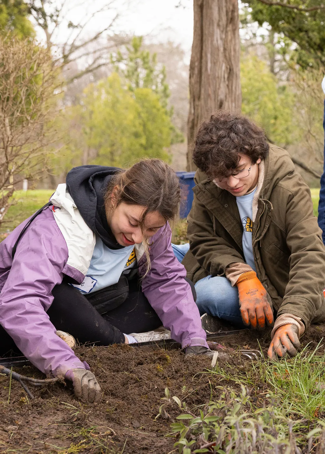 Two students digging in the ground at an orange seeds event.