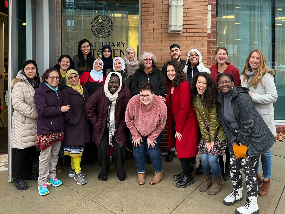 A group of people standing outside a building, smiling.