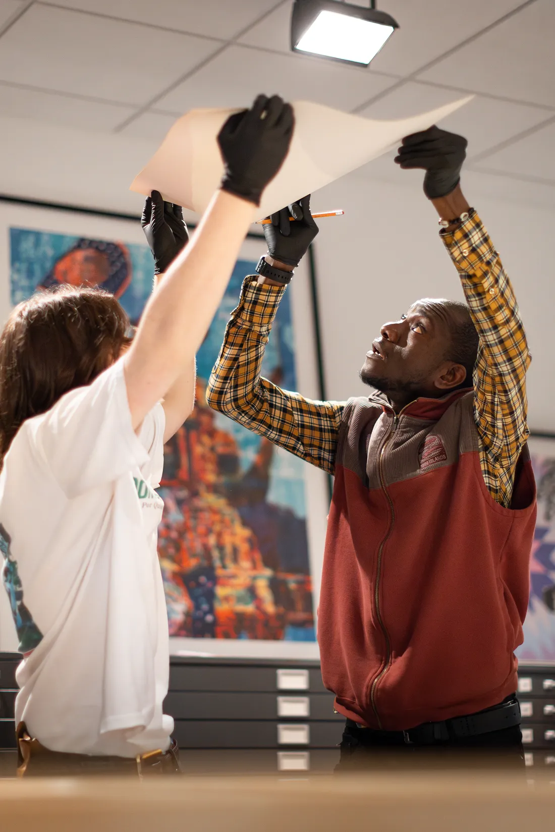People holding up an art print to examine it.