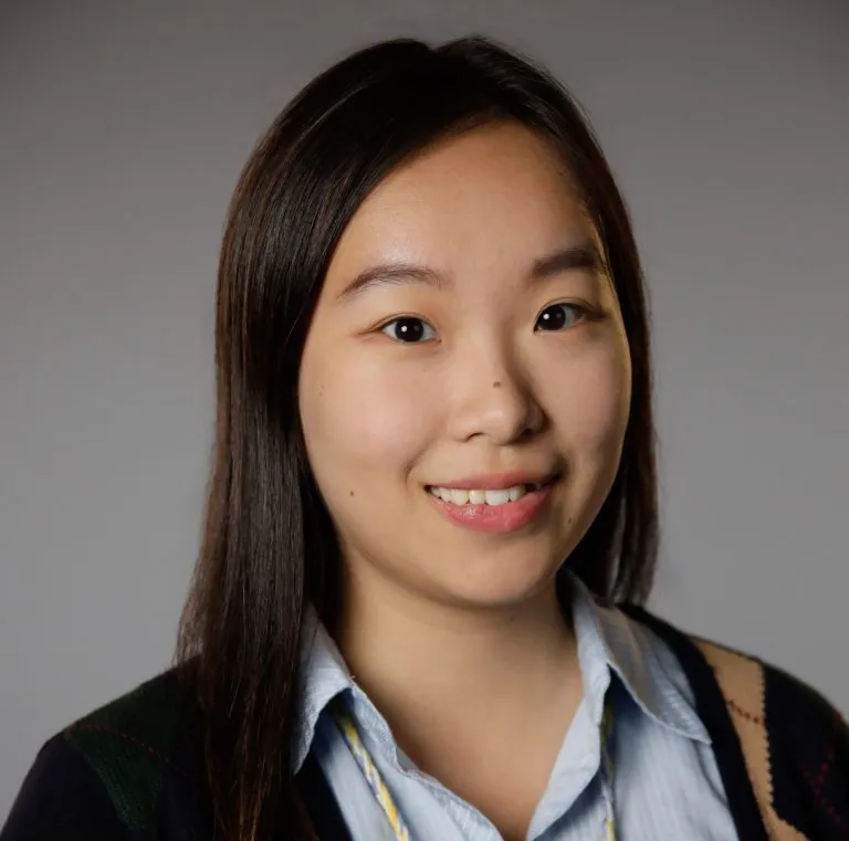 Jianya Jiang smiling in front of a grey background.
