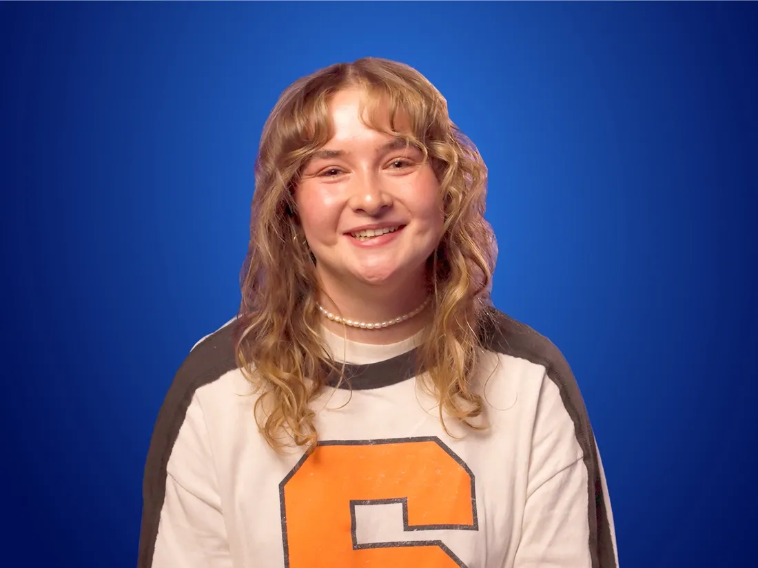 Megan Edenfeld's smiling in front of a Blue background.