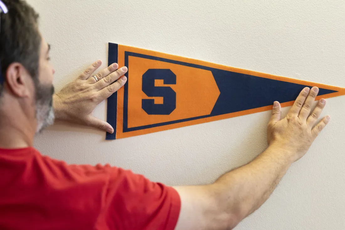 Courtland Newman hanging up a Syracuse University flag in his daughter's residence hall.