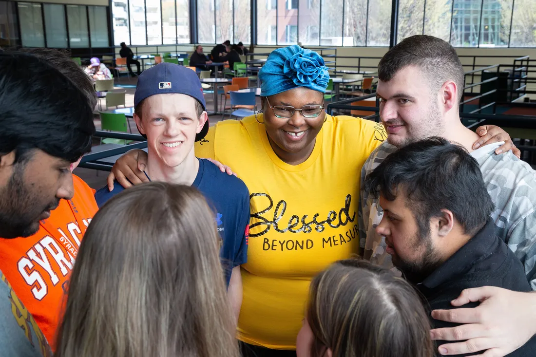 Shafreya Wilkins with others smiling and hugging.