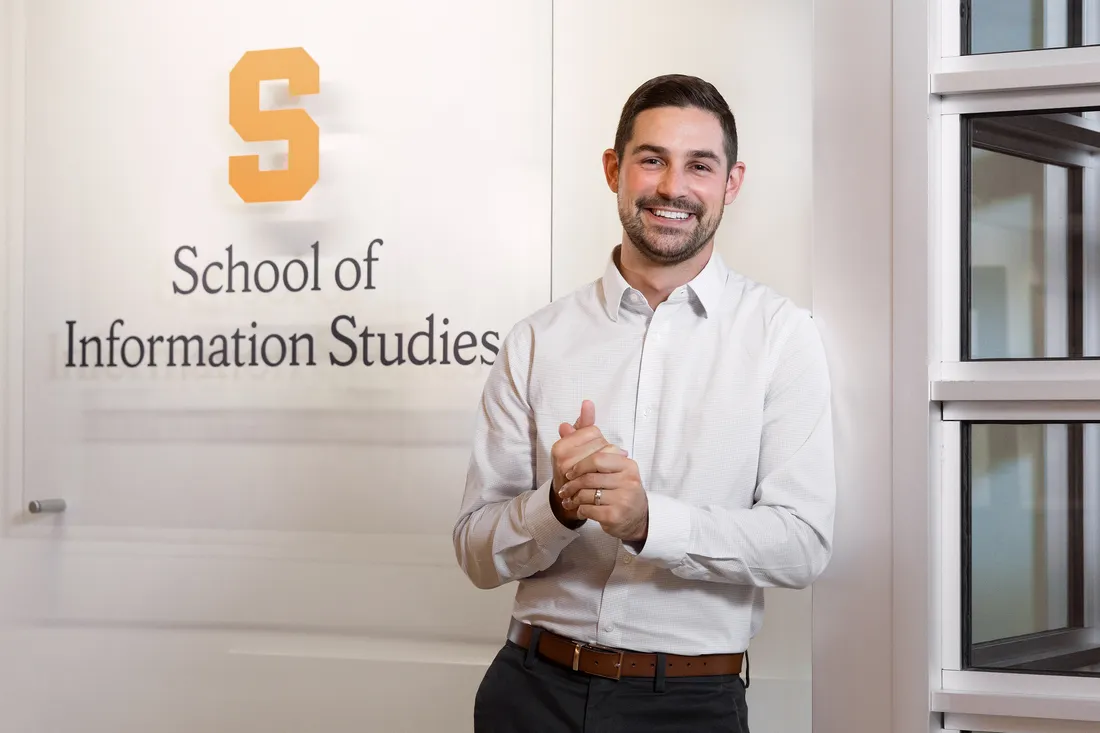 Portrait of Kelly in front of an iSchool sign.