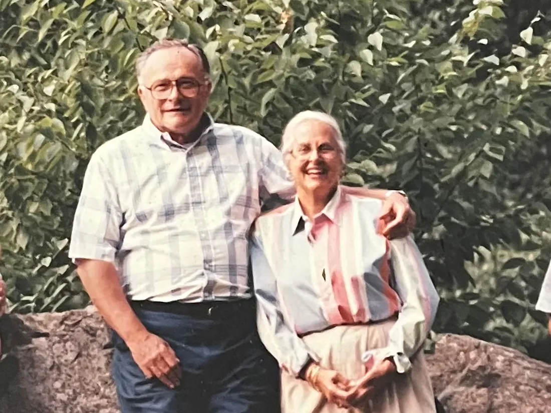 Two older people smiling and standing together.