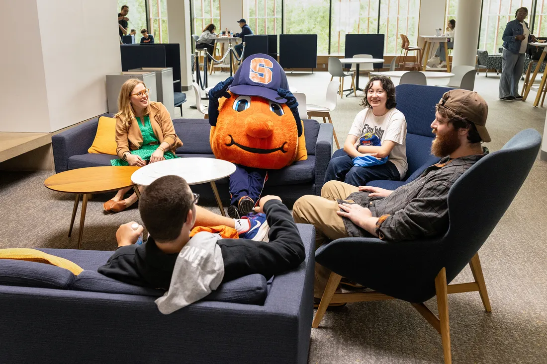 People sitting on couches with the mascot Otto.