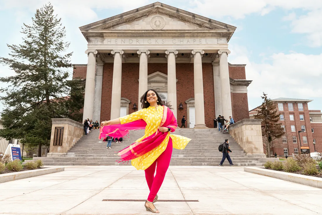 Landscape shot of Gharat spinning in front of a building with columns.