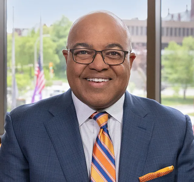 Michael T. Tirico smiling in a suit.
