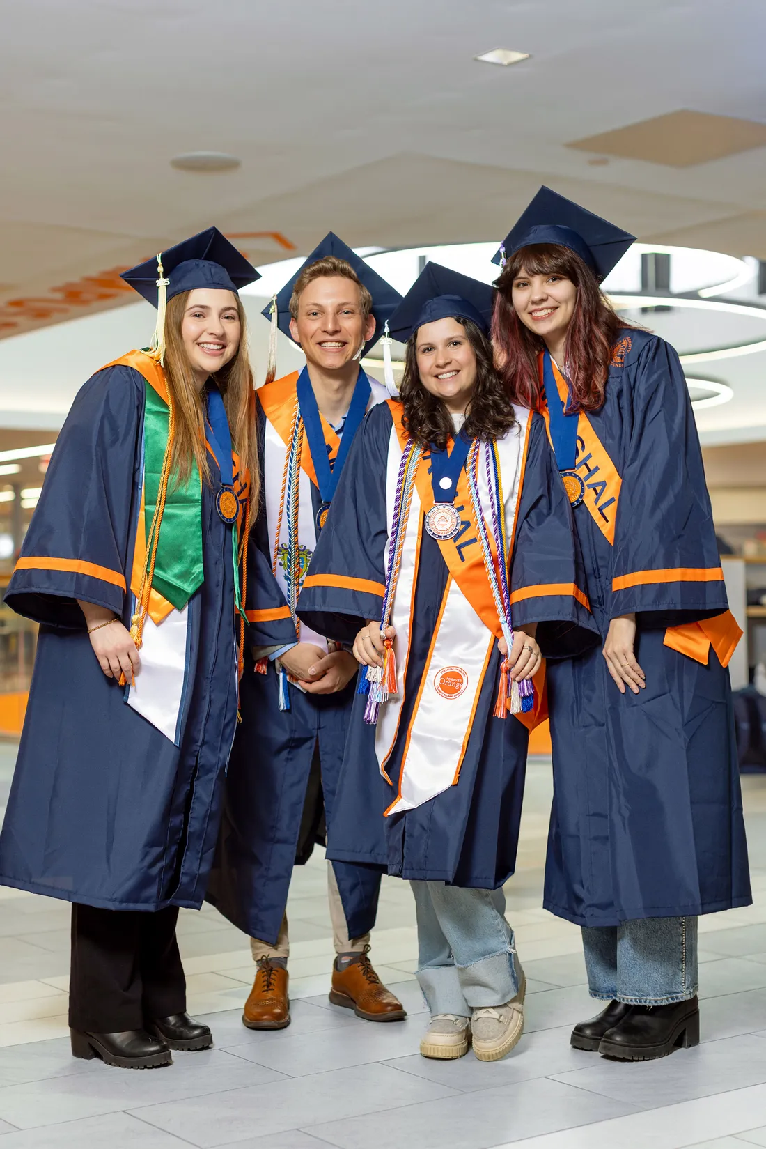 Class Marshals standing and smiling in their academic regalia.