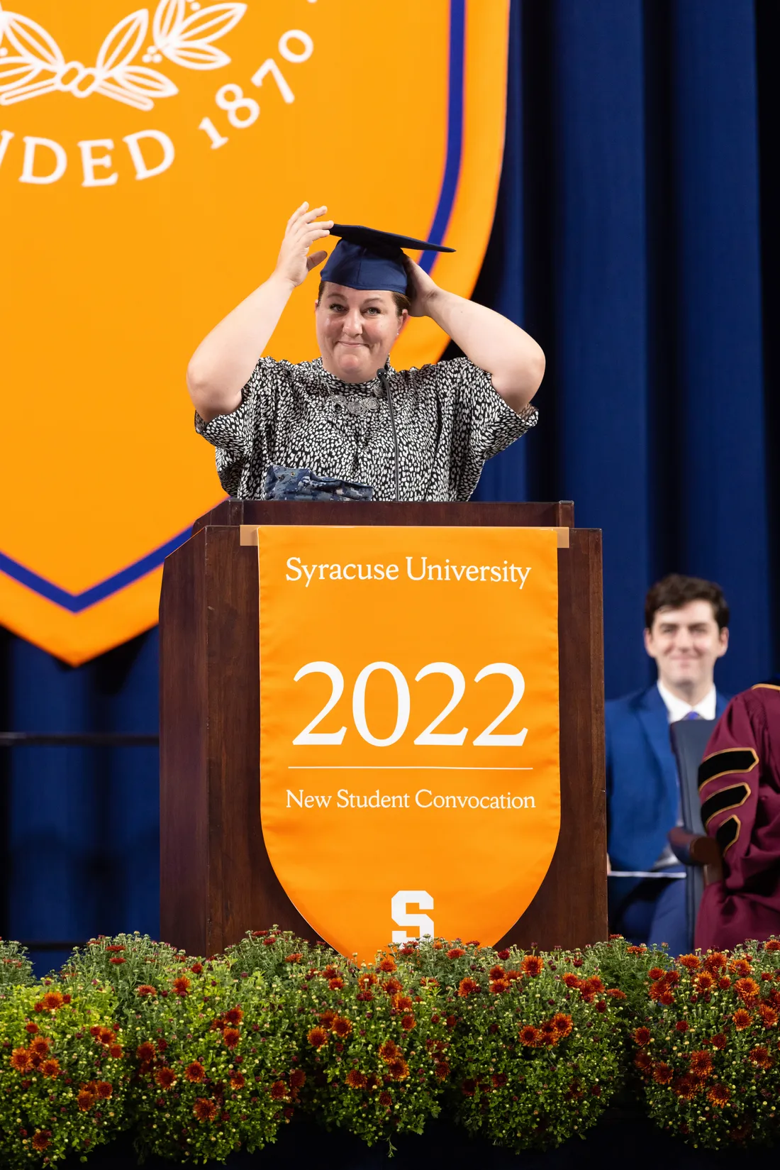 Female student wearing gown cap standing in podium.