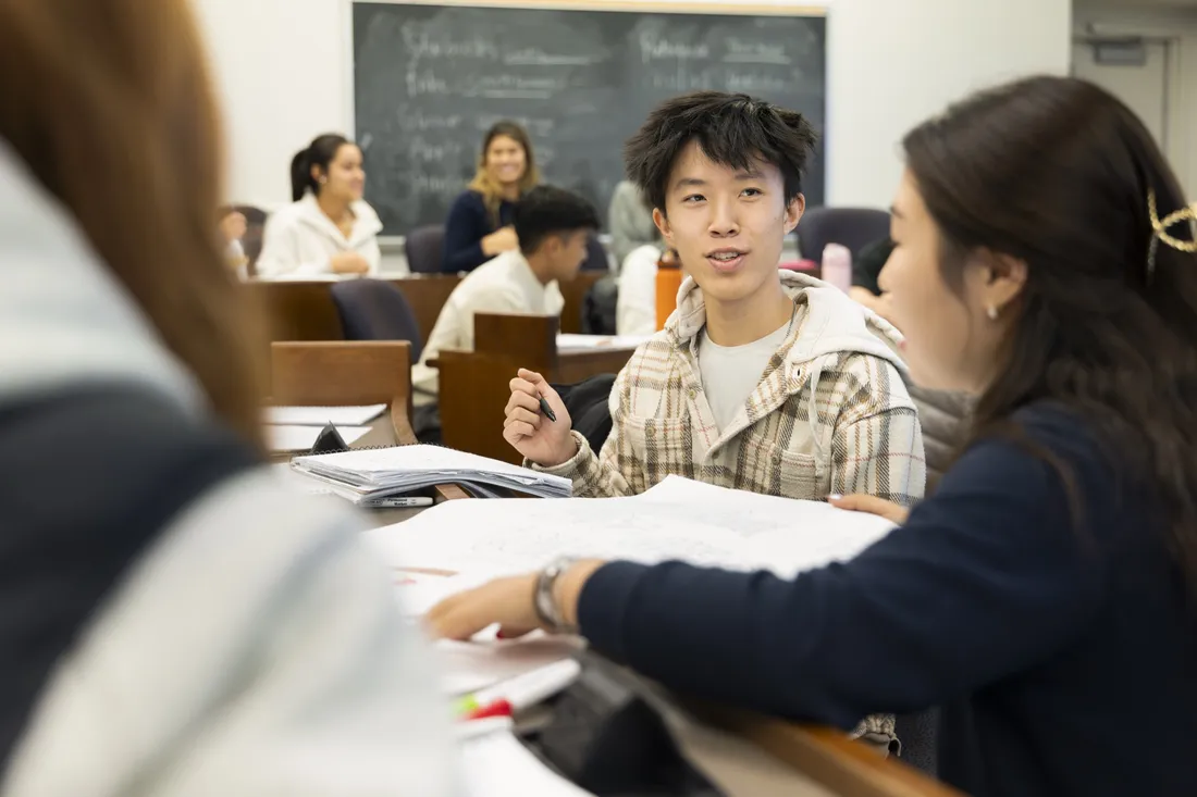 Students sitting at a table speaking.
